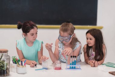 İlköğretim Okulu Bilim Sınıfı: Coşkulu Öğretmen Kimyayı Çeşitli Çocuklar Grubu 'na Açıkladı, Küçük Çocuk Kimyasalları Beakers' a Karıştırdı. Çocuklar ilgiyle öğrenir. Yavaş çekim.
