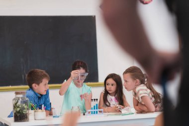 İlköğretim Okulu Bilim Sınıfı: Coşkulu Öğretmen Kimyayı Çeşitli Çocuklar Grubu 'na Açıkladı, Küçük Çocuk Kimyasalları Beakers' a Karıştırdı. Çocuklar ilgiyle öğrenir. Yavaş çekim.