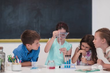 İlköğretim Okulu Bilim Sınıfı: Coşkulu Öğretmen Kimyayı Çeşitli Çocuklar Grubu 'na Açıkladı, Küçük Çocuk Kimyasalları Beakers' a Karıştırdı. Çocuklar ilgiyle öğrenir. Yavaş çekim.