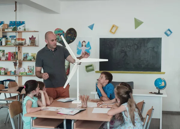 Elementary School Stem Robotics Classroom: Diverse Group of Children Building and Programming windmill ecology robot concept. Together, Talking and Working as a Team. Creative Robotics Engineering.