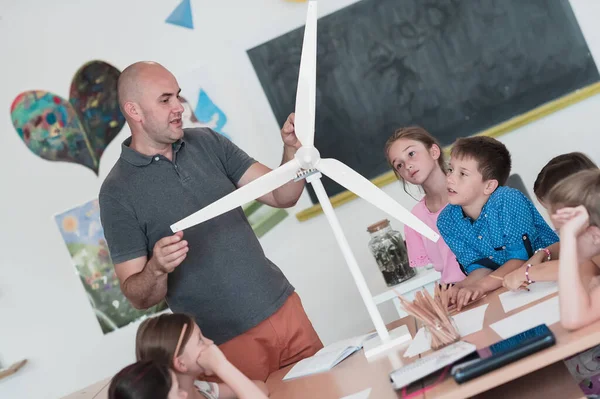 Elementary School Stem Robotics Classroom: Diverse Group of Children Building and Programming windmill ecology robot concept. Together, Talking and Working as a Team. Creative Robotics Engineering.