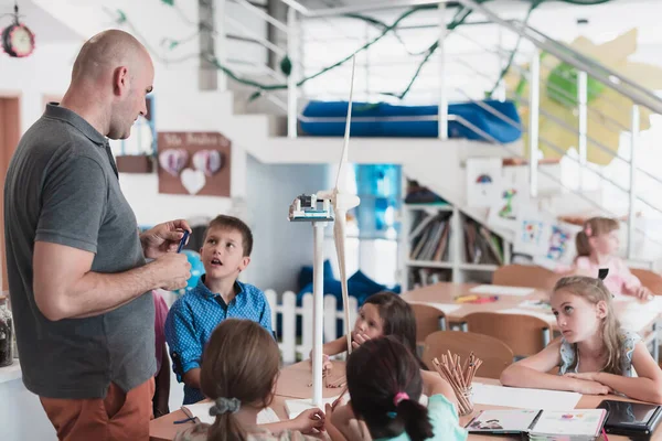 Elementary School Stem Robotics Classroom: Diverse Group of Children Building and Programming windmill ecology robot concept. Together, Talking and Working as a Team. Creative Robotics Engineering.