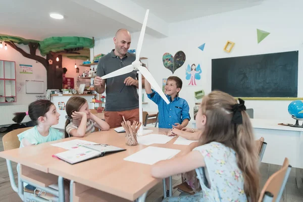 Elementary School Stem Robotics Classroom: Diverse Group of Children Building and Programming windmill ecology robot concept. Together, Talking and Working as a Team. Creative Robotics Engineering.