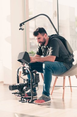 Video operatörü. Videografi. Çekim. Bir adam video çekiyor. Bir kameramanın işi. Profesyonel bir kamerayla tripodla çekim yapmak. Bir adam profesyonel bir kamerada çekim yapıyor. Videograf.