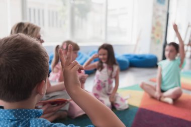 Reading time in elementary school or kindergarten, teacher reading a book to kids in elementary school or kindergarten. Selective focus. High quality photo
