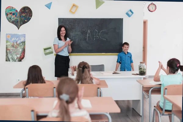 Elementary School Female Teacher Helps Child Student While Writing Answer — Foto Stock