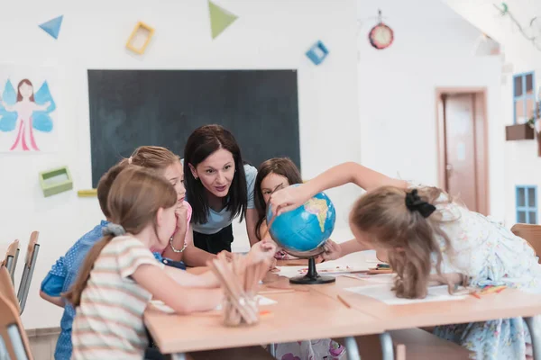Female Teacher Kids Geography Class Looking Globe Side View Group — Stok Foto