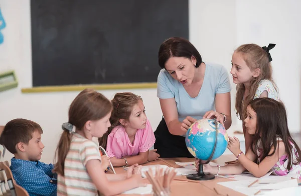 Female Teacher Kids Geography Class Looking Globe Side View Group — Foto Stock