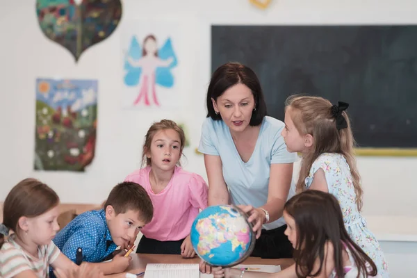 Female Teacher Kids Geography Class Looking Globe Side View Group — Foto Stock