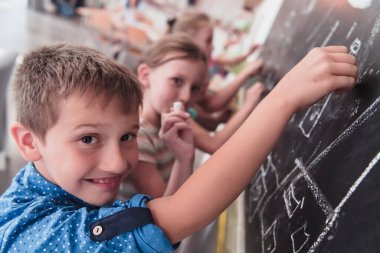 Children write and draw on the blackboard in elementary school while learning the basics of education. High quality photo