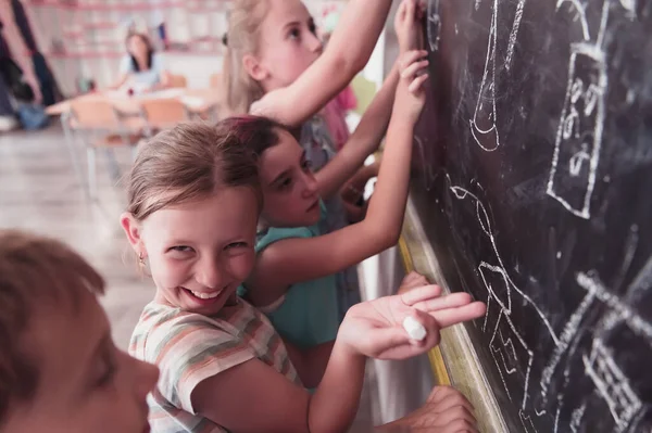 Children write and draw on the blackboard in elementary school while learning the basics of education. High quality photo