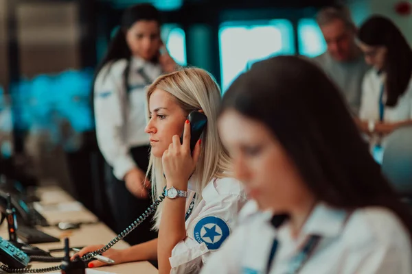 Female security guard operator talking on the phone while working at the workstation with multiple displays Security guards working on multiple monitors. High quality photo