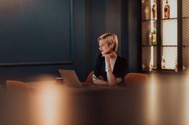 Businesswoman sitting in a cafe while focused on working on a laptop and participating in online meetings. Selective focus. High quality photo. 