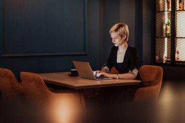Businesswoman sitting in a cafe while focused on working on a laptop and participating in online meetings. Selective focus. High quality photo. 