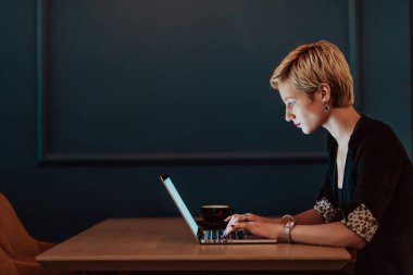 Businesswoman sitting in a cafe while focused on working on a laptop and participating in online meetings. Selective focus. High quality photo. 