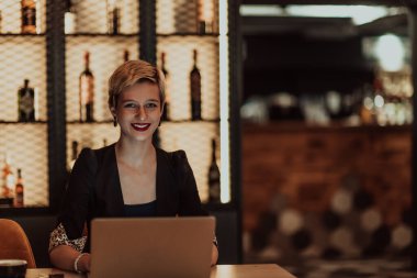 Businesswoman sitting in a cafe while focused on working on a laptop and participating in online meetings. Selective focus. High quality photo. 