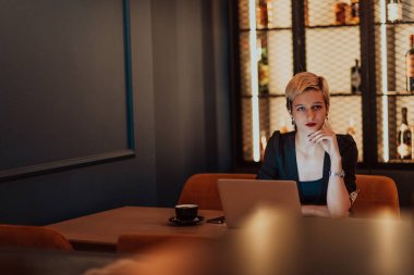 Businesswoman sitting in a cafe while focused on working on a laptop and participating in online meetings. Selective focus. High quality photo. 