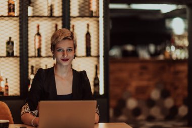 Businesswoman sitting in a cafe while focused on working on a laptop and participating in online meetings. Selective focus. High quality photo. 