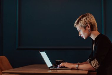 Businesswoman sitting in a cafe while focused on working on a laptop and participating in online meetings. Selective focus. High quality photo. 