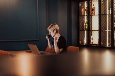 Businesswoman sitting in a cafe while focused on working on a laptop and participating in online meetings. Selective focus. High quality photo. 