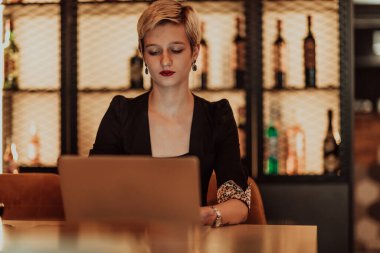Businesswoman sitting in a cafe while focused on working on a laptop and participating in online meetings. Selective focus. High quality photo. 