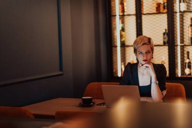 Businesswoman sitting in a cafe while focused on working on a laptop and participating in online meetings. Selective focus. High quality photo. 