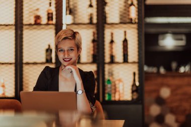 Businesswoman sitting in a cafe while focused on working on a laptop and participating in online meetings. Selective focus. High quality photo. 