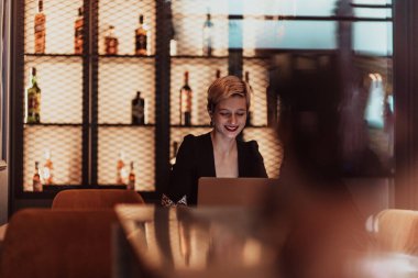 Businesswoman sitting in a cafe while focused on working on a laptop and participating in online meetings. Selective focus. High quality photo. 