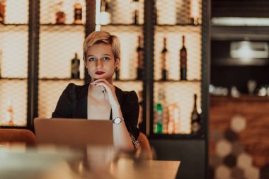 Businesswoman sitting in a cafe while focused on working on a laptop and participating in online meetings. Selective focus. High quality photo. 