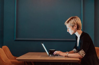 Businesswoman sitting in a cafe while focused on working on a laptop and participating in online meetings. Selective focus. High quality photo. 