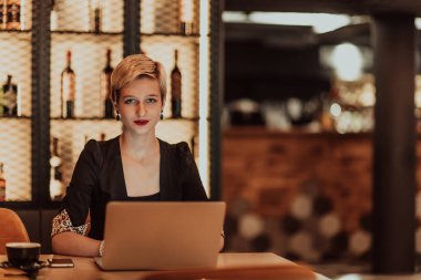 Businesswoman sitting in a cafe while focused on working on a laptop and participating in online meetings. Selective focus. High quality photo. 