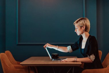 Businesswoman sitting in a cafe while focused on working on a laptop and participating in online meetings. Selective focus. High quality photo. 