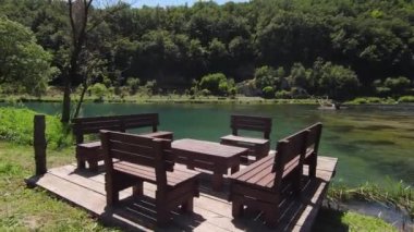 Empty Benches Sit Near the Una river on a beautiful sunny day in Bosnia and Herzegovina. Relaxing calm scenery green nature fresh drinking water. High quality 4k footage