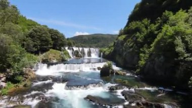 Fast extreme dive flight over the epic waterfall at exotic Una river aerial view. FPV sport drone speed movement nature at vegetation greenery wild environment. High quality 4k footage
