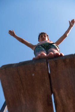 young teen boy ready for a jump in the river on a summer sunny day on vacation superhero shot with selective focus on water drops. High quality photo