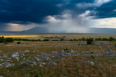 Panoramic view of idyllic mountain scenery with fresh green meadows in bloom on a beautiful sunny day in springtime, Rainfall in the distance, High quality photo