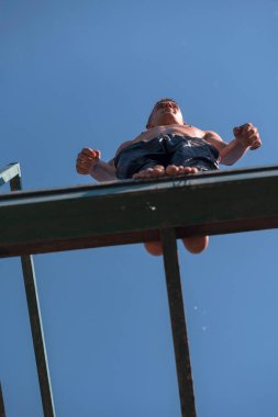 young teen boy ready for a jump in the river on a summer sunny day on vacation superhero shot with selective focus on water drops. High quality photo