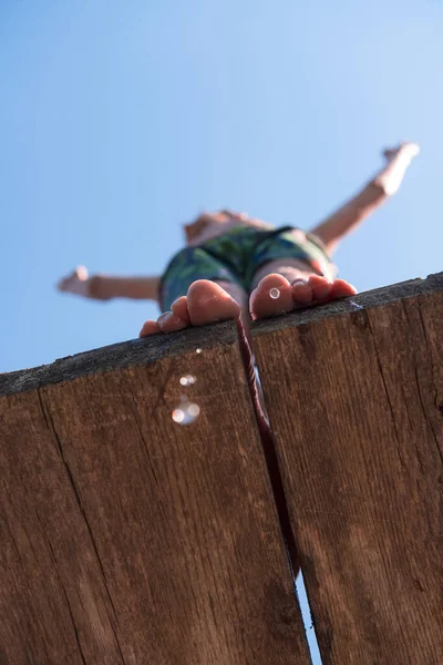 young teen boy ready for a jump in the river on a summer sunny day on vacation superhero shot with selective focus on water drops. High quality photo