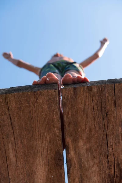 young teen boy ready for a jump in the river on a summer sunny day on vacation superhero shot with selective focus on water drops. High quality photo