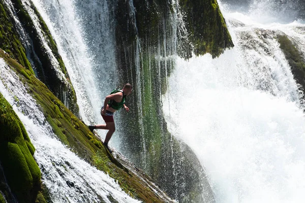 waterfall extreme brave man as superhero running jump and dive from the rock into the wild river water. High quality photo