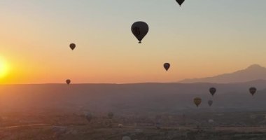 Aerial cinematic drone view of colorful hot air balloon flying over Cappadocia. Beautiful relaxing morning, summer sunrise, Anatolia region, Turkey