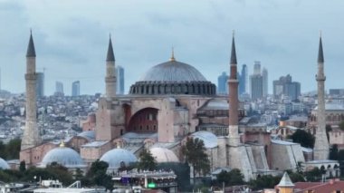 Establishing orbiting aerial drone shot of a Hagia Sophia Holy Grand Mosque with Bosphorus bridge and city skyline with a flag on the background in Fatih, Istanbul, Turkey at sunset. Cinematic footage