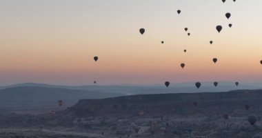 Aerial cinematic drone view of colorful hot air balloon flying over Cappadocia. Beautiful relaxing morning, summer sunrise, Anatolia region, Turkey