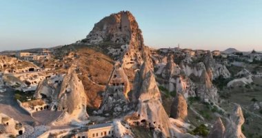 Aerial view of natural rock formations in the sunset, valley with cave houses in Cappadocia, Turkey. Natural landscape city lights at the night. Cinematic epic drone 4k hi quality footage.