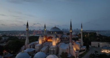 Establishing orbiting aerial drone shot of a Hagia Sophia Holy Grand Mosque with Bosphorus bridge and city skyline with a flag on the background in Fatih, Istanbul, Turkey at sunset. Cinematic footage