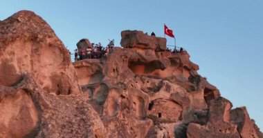 Aerial view of natural rock formations in the sunset, valley with cave houses in Cappadocia, Turkey. Natural landscape city lights at the night. Cinematic epic drone 4k hi quality footage.