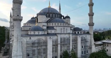 Establishing orbiting aerial drone shot of a Hagia Sophia Holy Grand Mosque with Bosphorus bridge and city skyline with a flag on the background in Fatih, Istanbul, Turkey at sunset. Cinematic footage