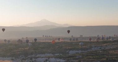 Aerial cinematic drone view of colorful hot air balloon flying over Cappadocia. Beautiful relaxing morning, summer sunrise, Anatolia region, Turkey