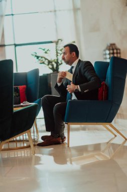 A modern businessman in a suit sits in a modern office and examines documents. Selective focus. High quality photo