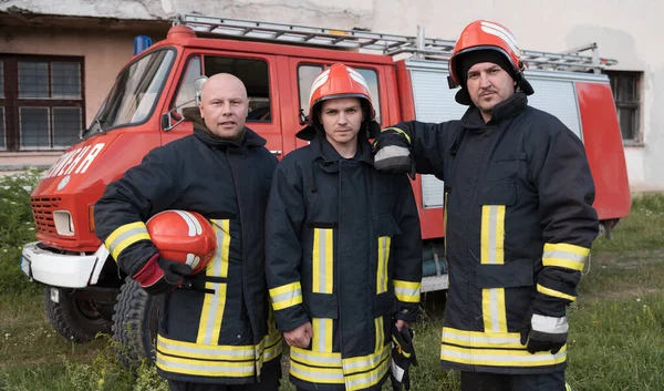 Group of fire fighters standing confident after a well done rescue operation. Firemen ready for emergency service. High quality photo